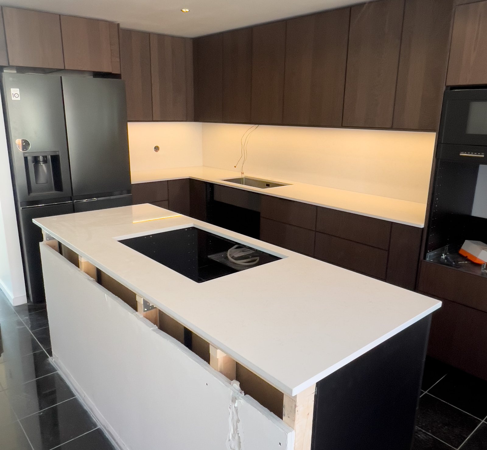 Technistone Noble Supreme White -kvartsitaso tummassa keittiössä – Stoneks Finlandin asennus